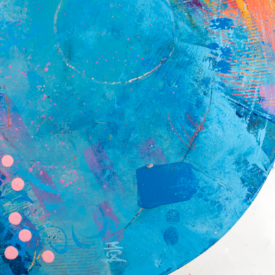 Close-up of an abstract circular painting. The dominant colors are vibrant orange and turquoise blue, blended with streaks of yellow, pink, and purple. The texture appears layered and brushstroked, creating a dynamic visual effect.
